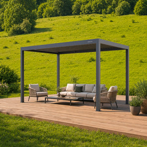 Pergola 4 antracite con tetto a lamelle su una pedana in legno con divano e poltrone, in un prato verde in collina